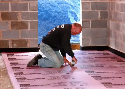Charlie Utermohle on hands and knees at work in a building