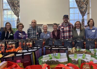 group of volunteers standing behind rows of grocery bags